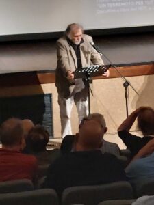 Uomo parla al pubblico in teatro